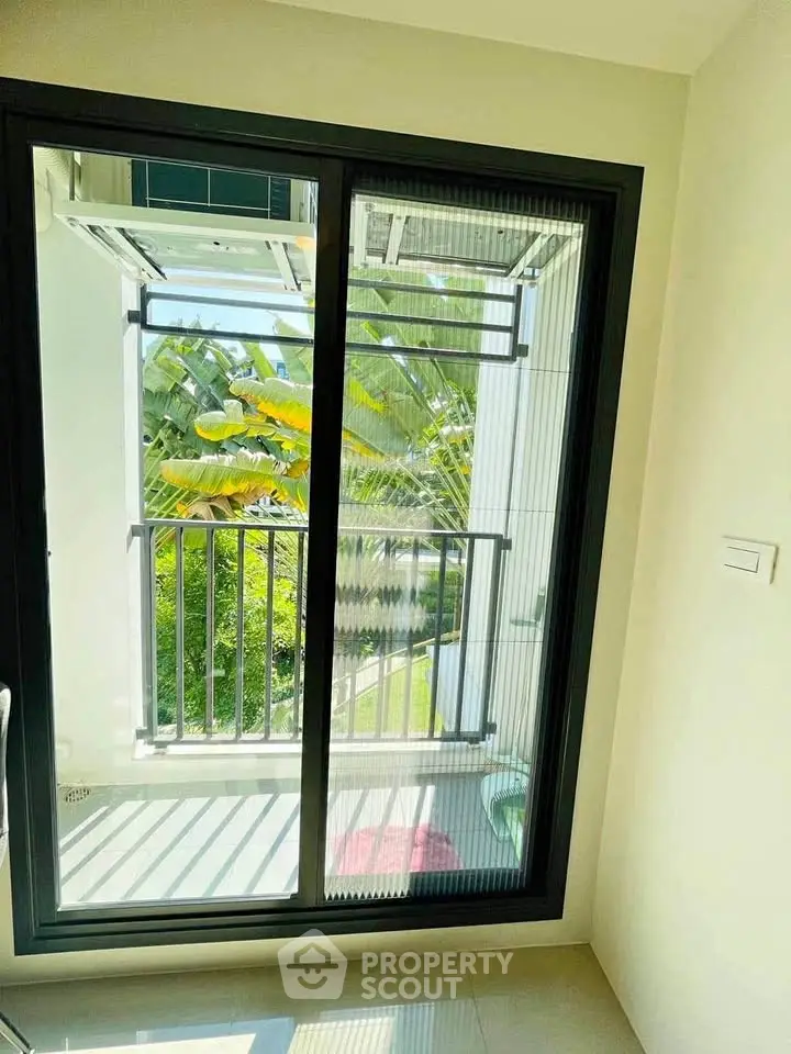 Bright room with sliding glass door leading to a small balcony with lush green view.