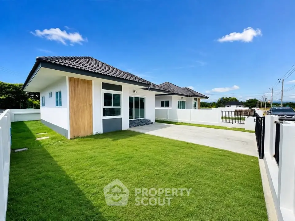 Charming single-story house with spacious lawn and modern design under clear blue sky.
