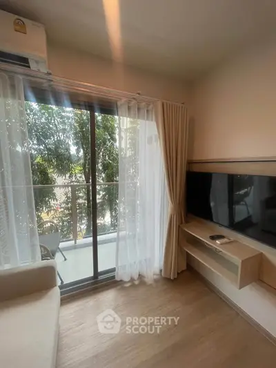 Cozy living room with balcony view and modern TV setup, perfect for relaxation.