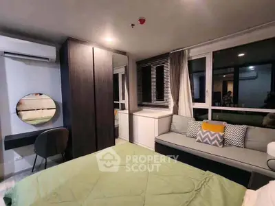 Modern bedroom with stylish decor, featuring a cozy seating area and large windows for natural light.