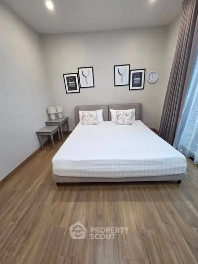 Modern bedroom with stylish decor and wooden flooring, featuring a cozy bed and elegant wall art.