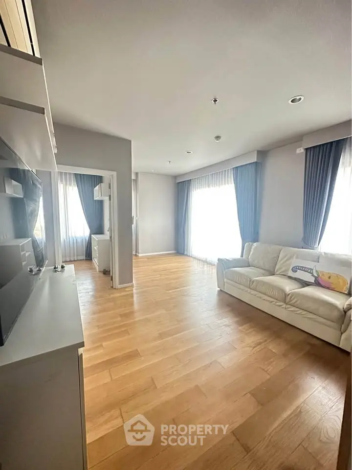 Spacious living room with hardwood floors and natural light, featuring a cozy sofa and modern decor.