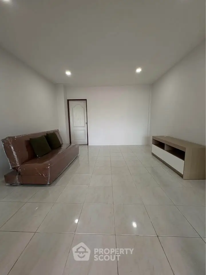 Spacious minimalist living room with tiled flooring and modern furniture.