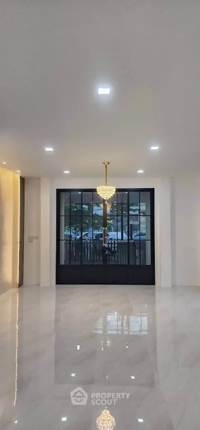 Luxurious empty living room with chandelier and large windows