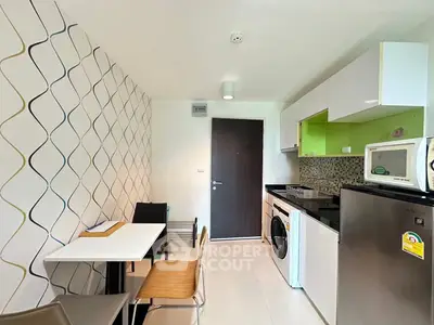 Modern kitchen with dining area, featuring washing machine and sleek appliances.