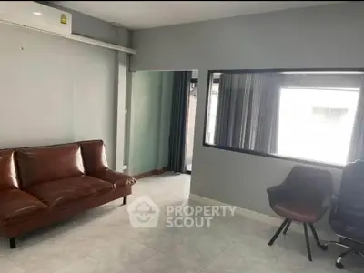 Modern living room with leather sofa and office chairs, ideal for work and relaxation.