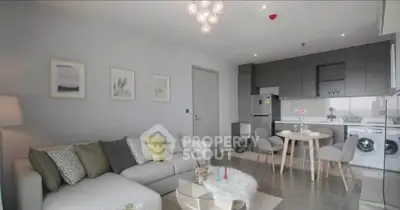 Modern living room with stylish decor and open kitchen layout, featuring a cozy sofa and dining area.