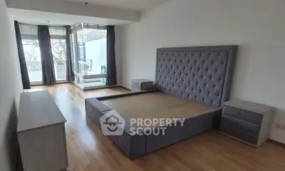Spacious bedroom with modern bed frame and large windows offering natural light.