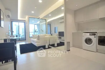Modern living room with mirrored wall and in-unit washing machine in a stylish apartment.
