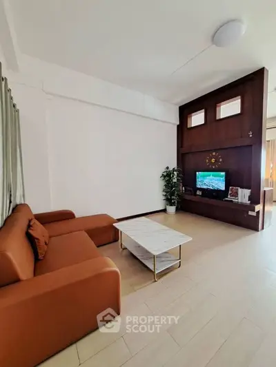 Spacious living room with modern brown sofa and sleek TV unit, perfect for relaxation and entertainment.
