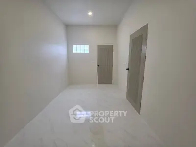 Minimalist room with marble flooring and two wooden doors, ideal for storage or utility use.