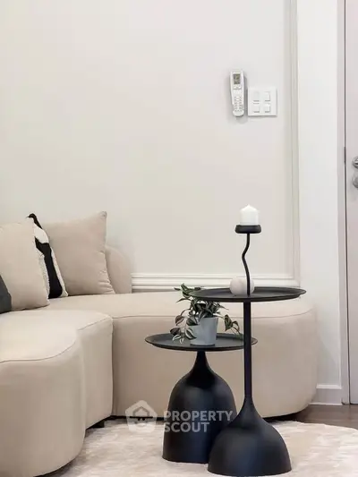 Modern living room with stylish beige sofa and black side tables, perfect for cozy relaxation.