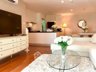 Elegant living room with modern decor and open kitchen layout, featuring cozy seating and stylish furnishings.