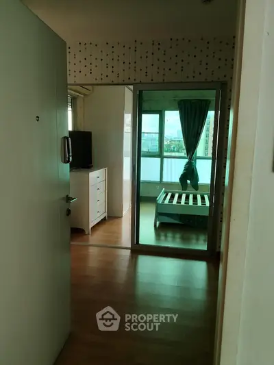 Spacious bedroom with wooden flooring and large window offering city views, perfect for urban living.