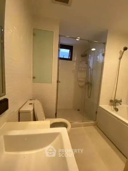Modern bathroom with glass shower and bathtub in a sleek apartment.