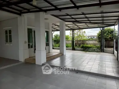 Spacious covered patio with tiled flooring and garden view, perfect for outdoor relaxation.