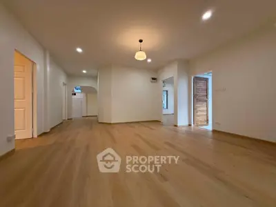 Spacious open-plan living area with elegant wooden flooring and modern lighting, perfect for family gatherings.