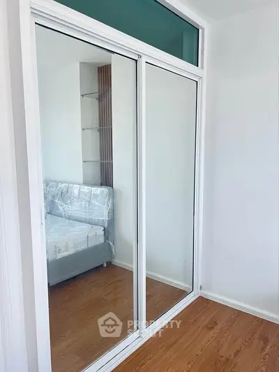 Modern bedroom with mirrored sliding closet doors and wooden flooring