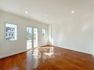 Spacious sunlit room with hardwood floors and large windows in modern home