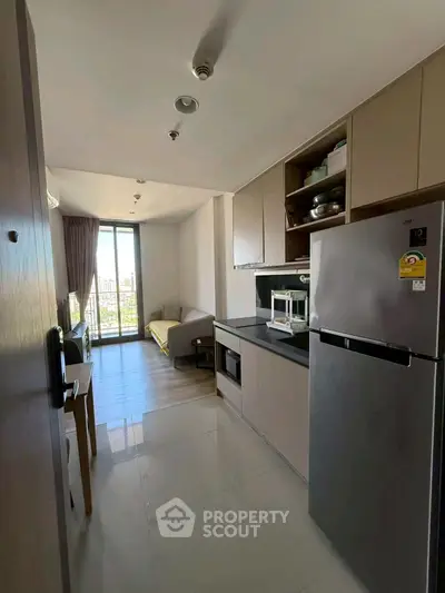Modern apartment kitchen with sleek appliances and open layout leading to a bright living area with city view.