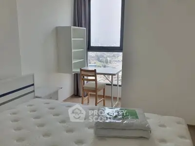 Bright bedroom with large window and city view, featuring a cozy bed and study area.