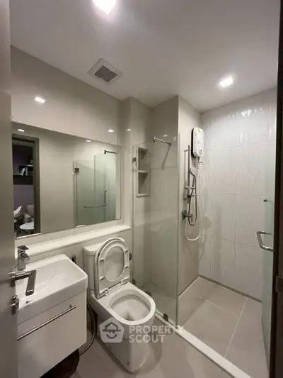 Modern bathroom with glass shower and sleek fixtures in contemporary apartment.