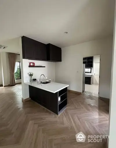 Modern open kitchen with island and elegant wooden flooring in a spacious apartment.