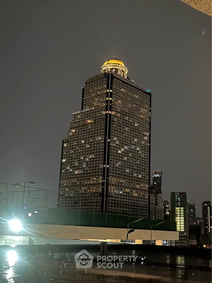 Stunning night view of a modern high-rise building with unique architecture and illuminated dome.