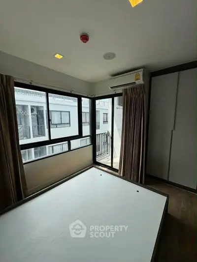 Modern bedroom with large windows and built-in wardrobe in a high-rise apartment.
