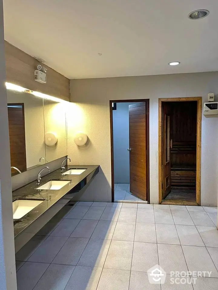 Modern bathroom with dual sinks and wooden sauna room in luxury property.