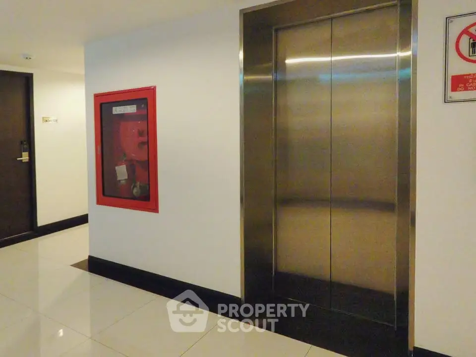 Modern building elevator with sleek stainless steel doors and polished tile flooring.