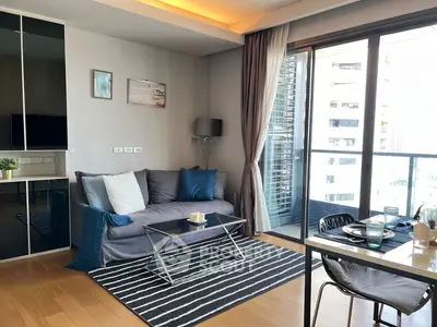 Modern living room with cozy sofa, stylish decor, and large windows offering city views.