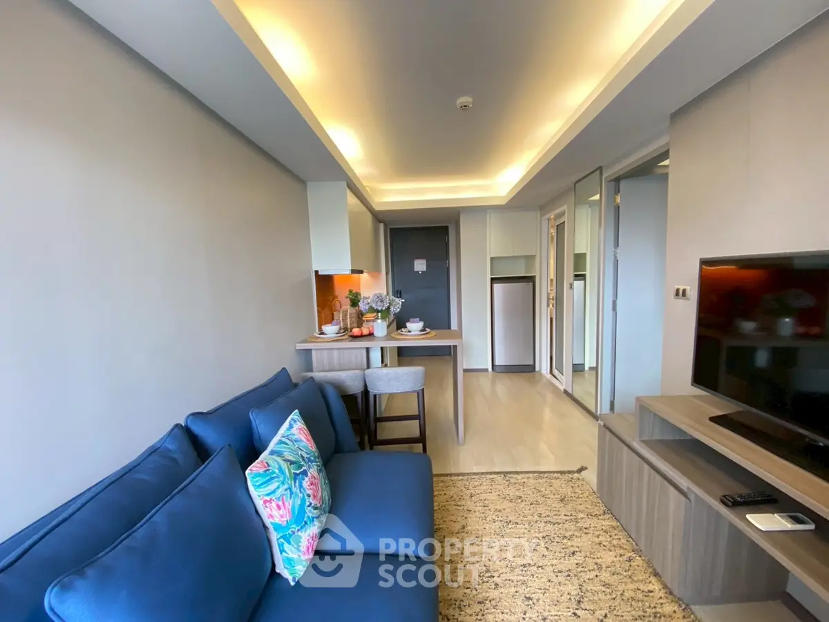 Modern living room with blue sofa and open kitchen layout in stylish apartment.