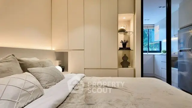 Modern bedroom with elegant decor and view into sleek kitchen area.