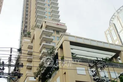 Modern high-rise building with unique architectural design and lush greenery