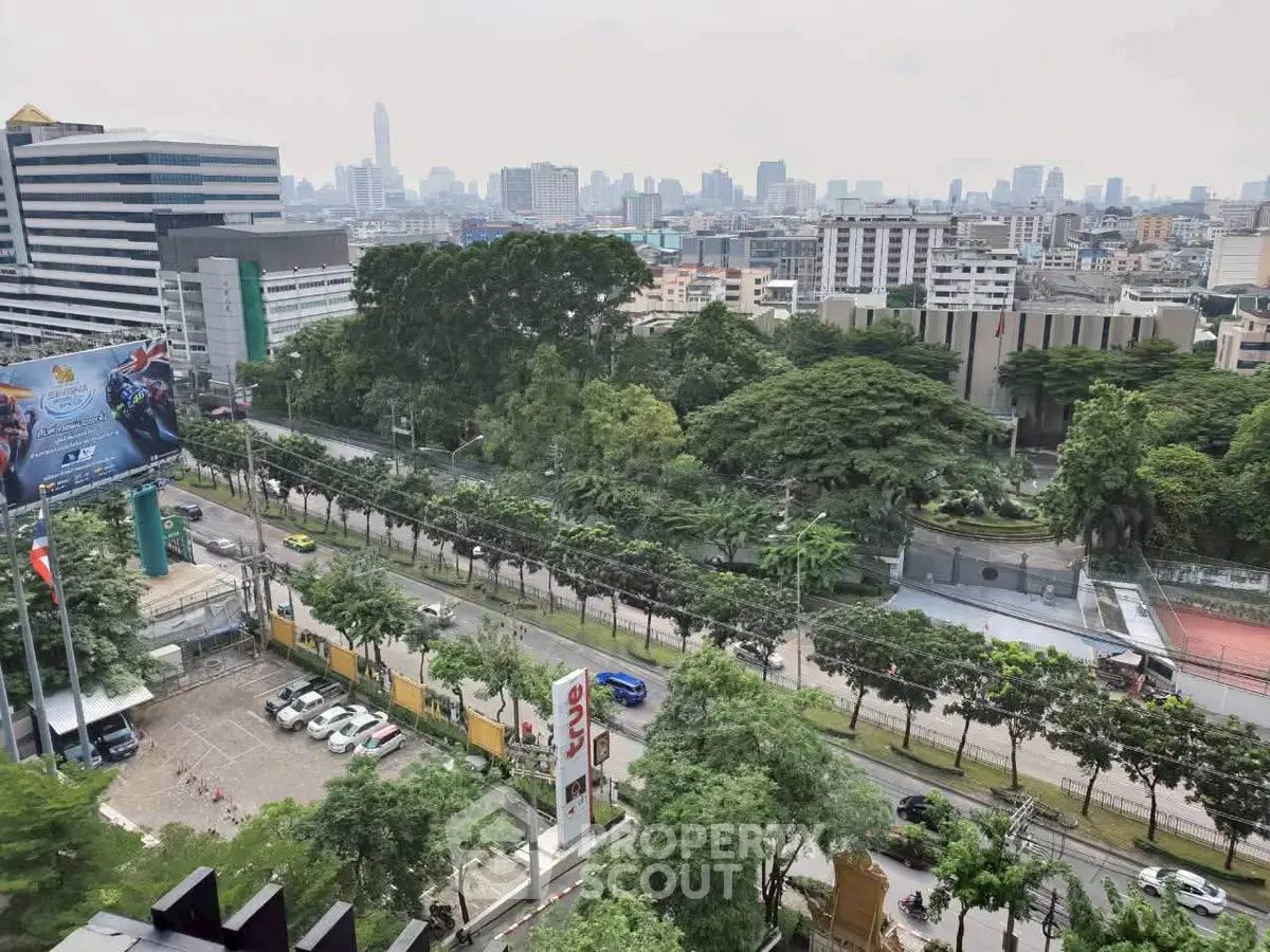 Stunning cityscape view from high-rise building with lush greenery and urban skyline.