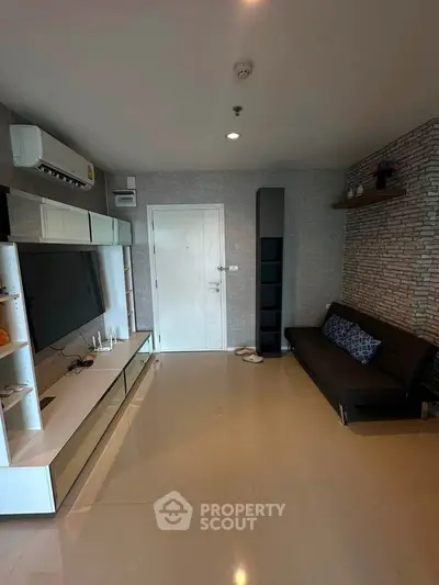 Modern living room with sleek furniture and stylish decor, featuring a large TV and air conditioning.
