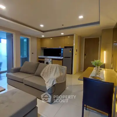 Modern living room with open kitchen, cozy sofa, and dining area in stylish apartment.