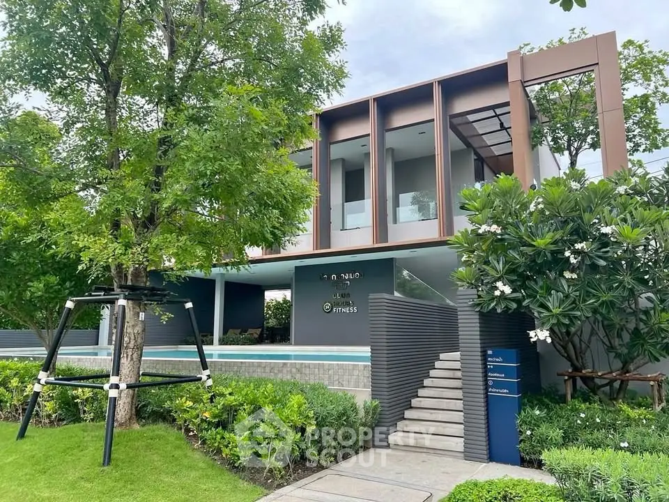 Modern building exterior with lush greenery and inviting entrance, showcasing contemporary architectural design.