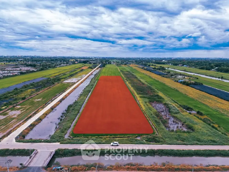 Expansive aerial view of prime real estate land with lush surroundings and clear skies, ideal for development.