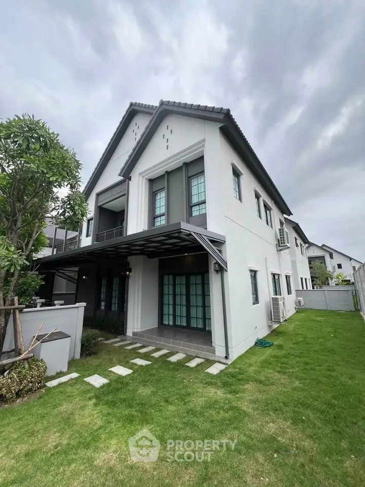 Elegant two-story house with modern design and lush green lawn, perfect for family living.