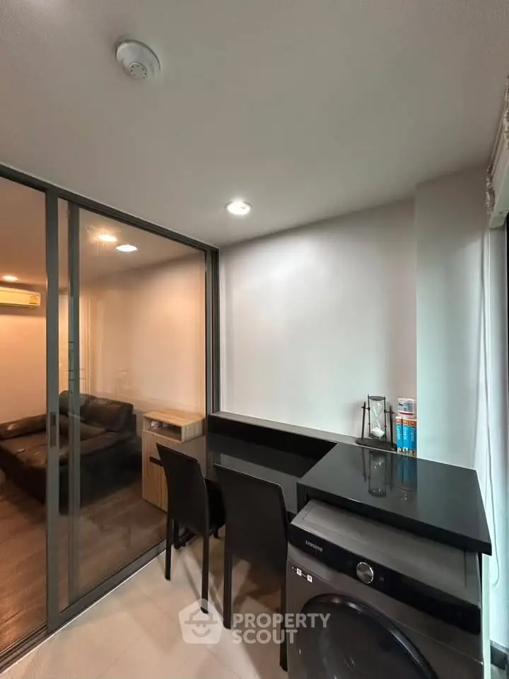 Modern apartment with sleek interior design featuring a compact dining area and washing machine.