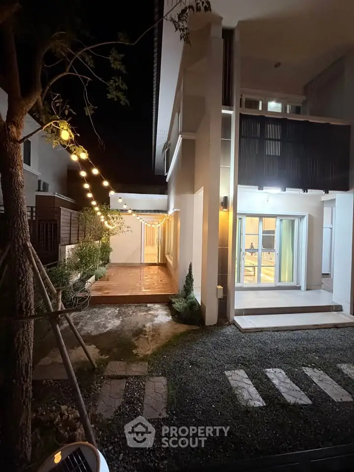 Charming modern home exterior with ambient lighting and spacious patio at night.