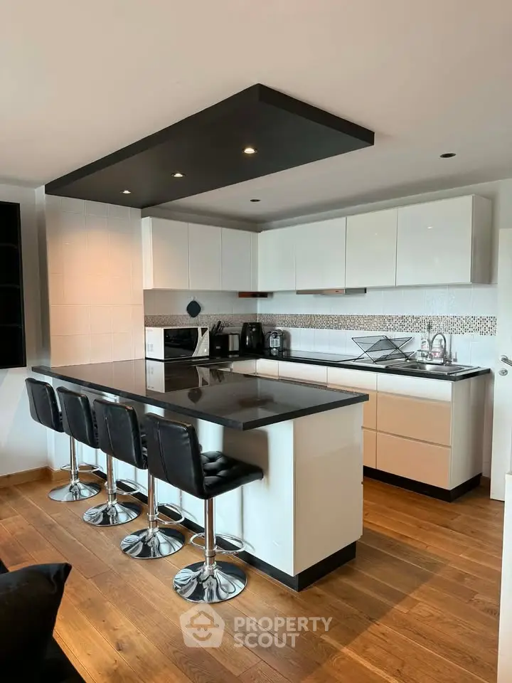 Modern kitchen with sleek black countertops and stylish bar stools