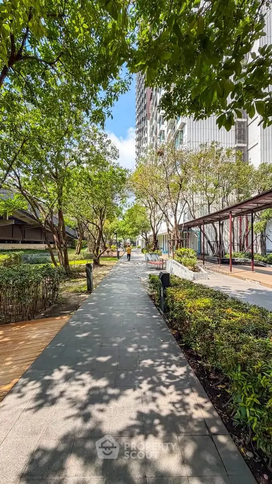 Beautiful garden pathway in modern residential complex with lush greenery and contemporary architecture.