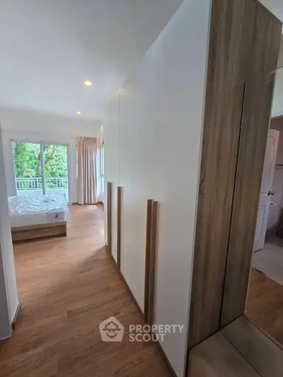 Spacious bedroom with wooden flooring and large wardrobe, featuring a serene view from the window.