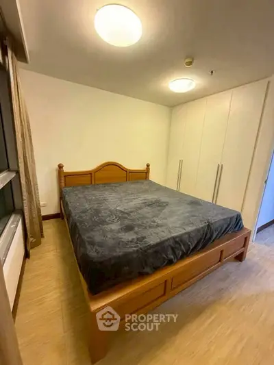 Spacious bedroom with wooden bed frame and ample closet space