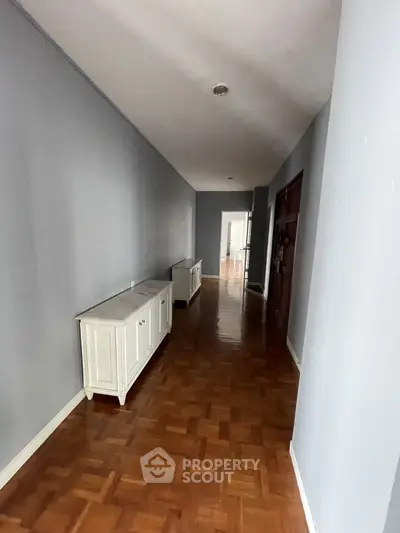 Spacious hallway with wooden flooring and elegant white cabinets.