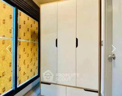 Modern bedroom with sleek wardrobe and large windows with patterned blinds.