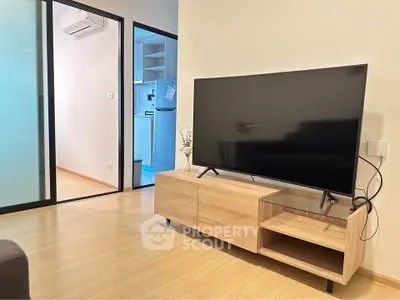 Modern living room with sleek TV setup and view into compact kitchen